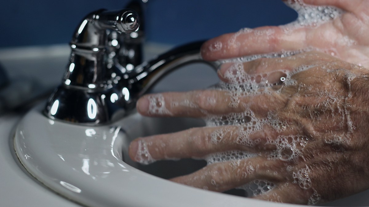 Manos enjabonadas lavándose bajo el grifo de un lavabo