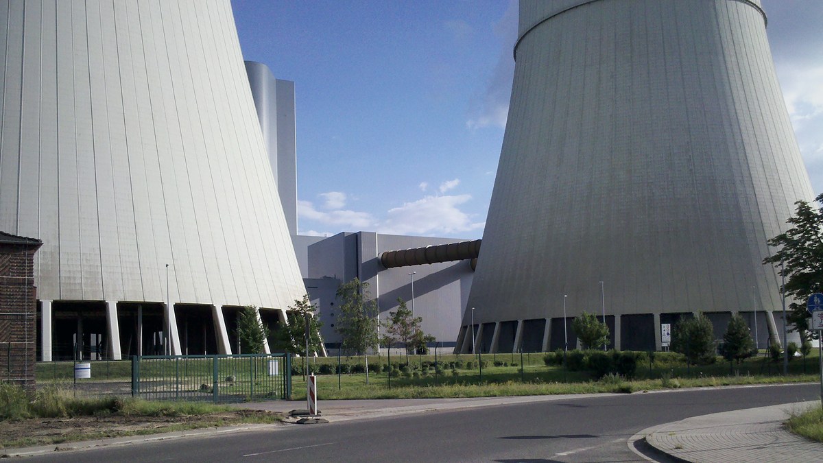 Base de dos grandes torres de refrigeración de hormigón junto a una carretera en una central industrial